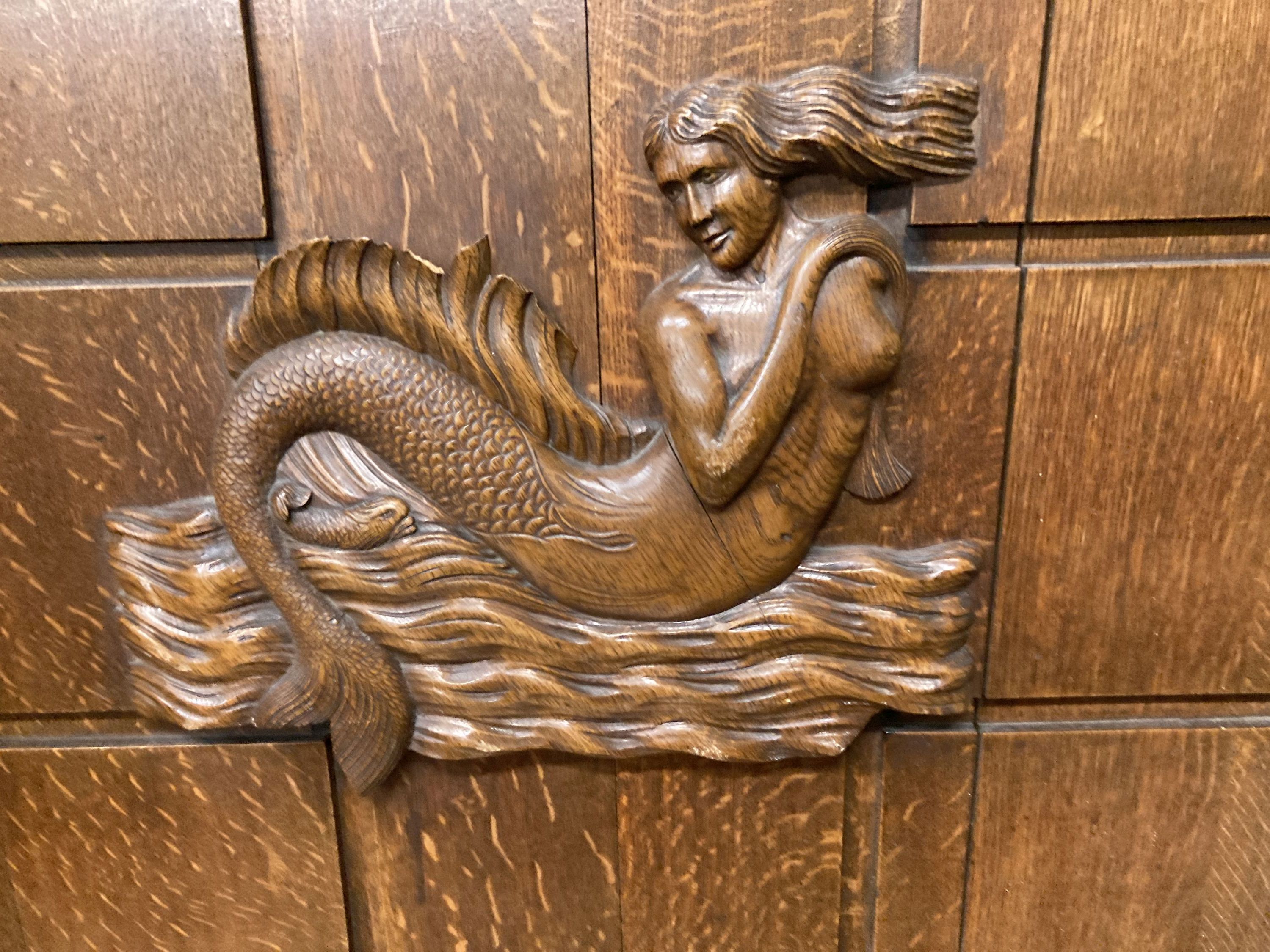 A mid 20th century rectangular oak panel carved with a mermaid formerly a cabinet door, width 81cm, depth 74cm